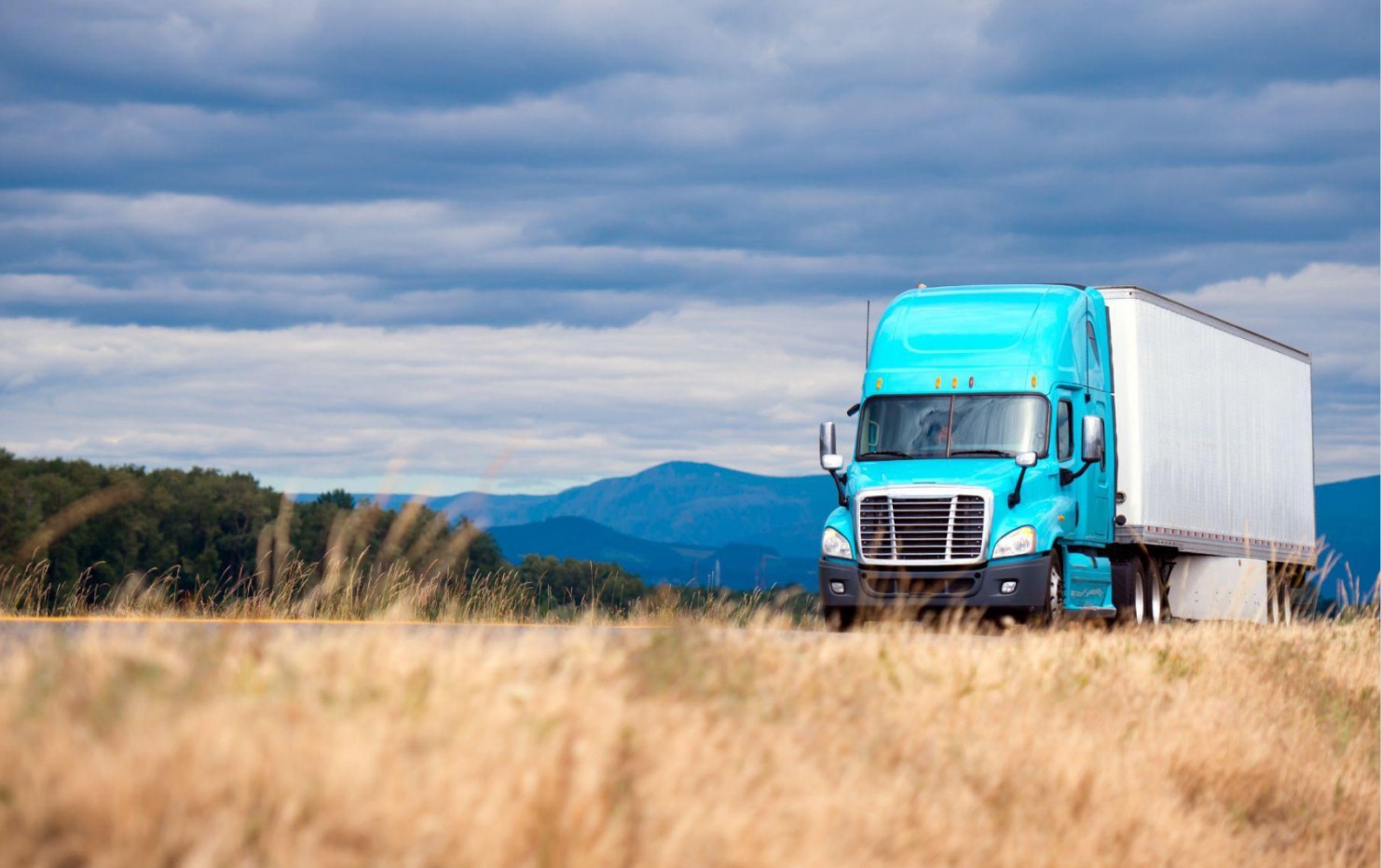 Blue semi-truck on a highway, representing national logistics and supply chain operations.
